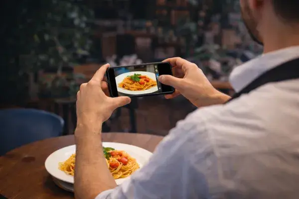 Waiter taking a photo of a dish for the digital menu